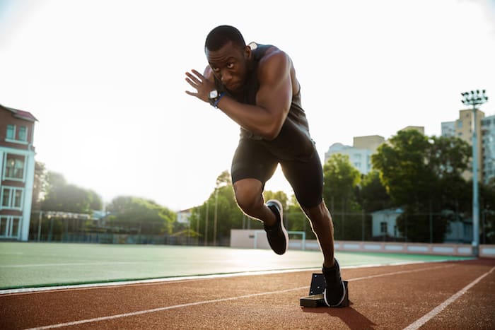 Young african runner running on racetrack at the athletics stadium