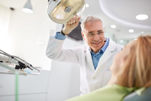 Senior male dentist adjust searchlight before starting work