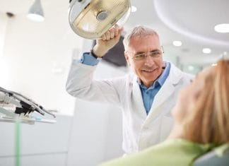 Senior male dentist adjust searchlight before starting work