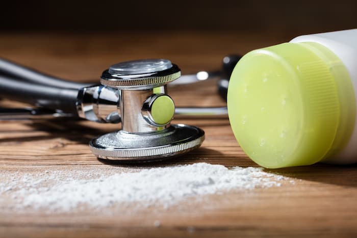 Close-up Of Spilled Talcum Powder And Stethoscope On Wooden Background