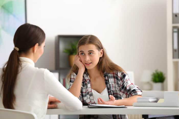 Young female psychologist working with teenager girl in office