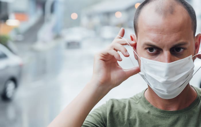 Man putting on a mask with a worried face. Virus concept