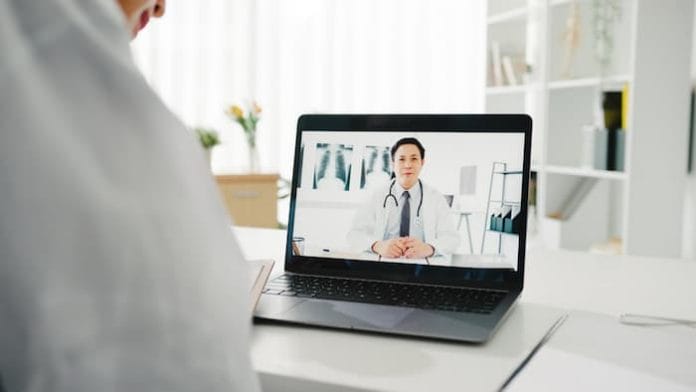 Young Asia lady doctor in white medical uniform using laptop talking video conference call with senior doctor at desk in health clinic or hospital. Social distancing, quarantine for corona virus.