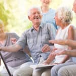 Group of smiling senior friends spending time together sitting in the park