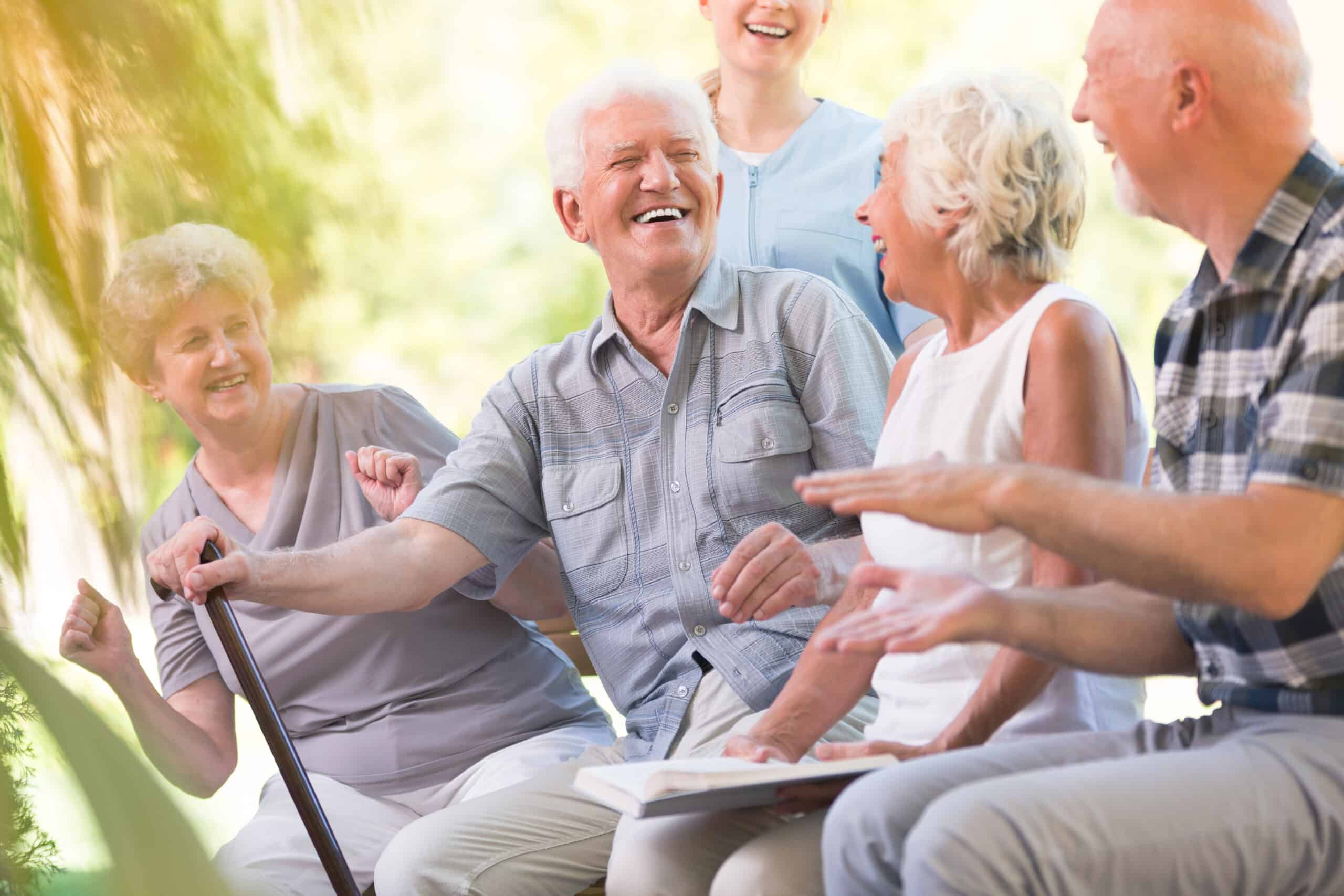 Group of smiling senior friends spending time together sitting in the park