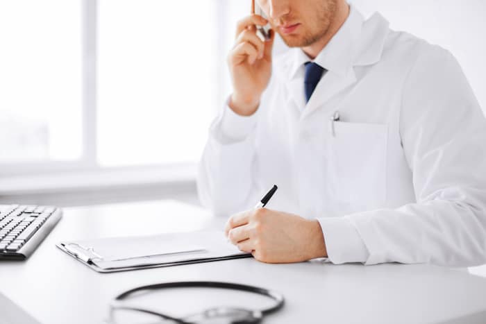healthcare, hospital and medical concept - male doctor writing prescription paper and capsules