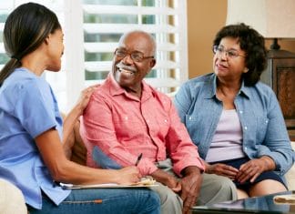 Nurse Making Notes During Home Visit With Senior Couple
