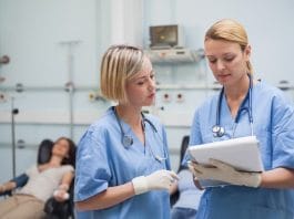 Nurses looking at a clipboard in hospital ward