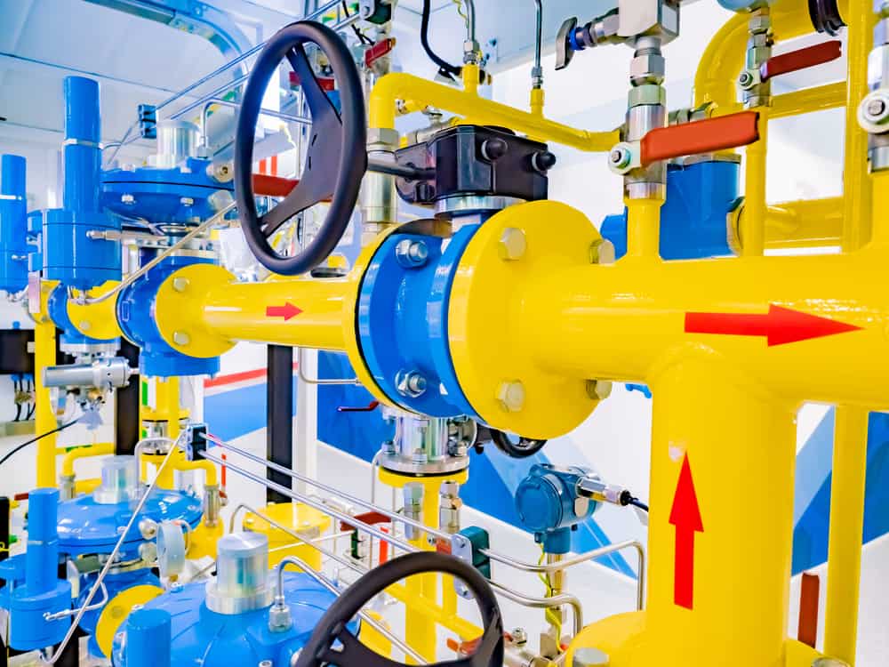 Yellow pipes inside the compressor station. Yellow pipes as a symbol of gas transportation. Arrows on the pipes show the direction of movement. Concept - supply of gas. Pressure regulating valves.