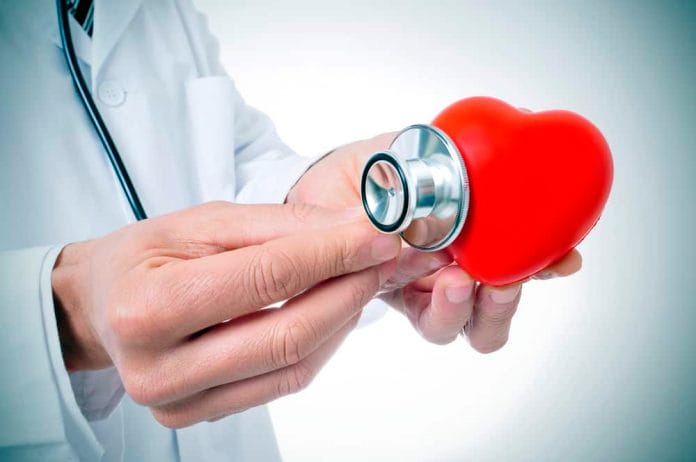a doctor auscultating a red heart with a stethoscope