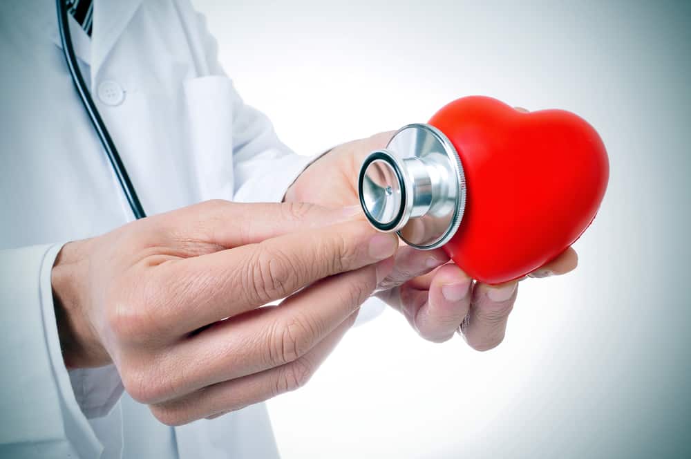 a doctor auscultating a red heart with a stethoscope