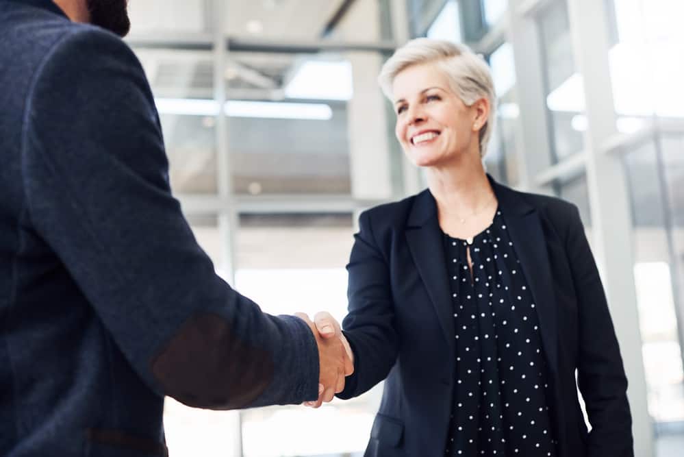 Cropped shot of two businesspeople shaking hands while standing in a modern office