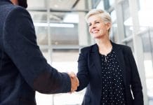Cropped shot of two businesspeople shaking hands while standing in a modern office