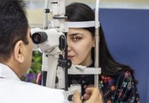 Male doctor ophthalmologist is checking eye vision of beautiful young woman in modern clinic. Doctor and patient in ophthalmology clinic.