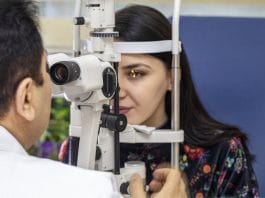Male doctor ophthalmologist is checking eye vision of beautiful young woman in modern clinic. Doctor and patient in ophthalmology clinic.