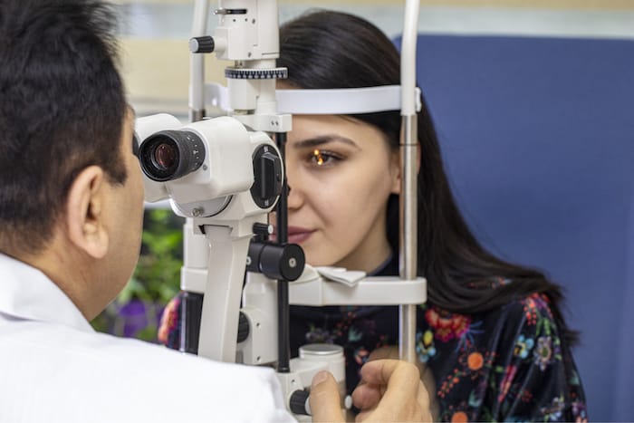 Male doctor ophthalmologist is checking eye vision of beautiful young woman in modern clinic. Doctor and patient in ophthalmology clinic.