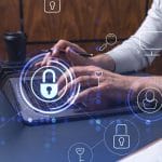 A programmer is typing a code on a keyboard to protect a cyber security from hacker attacks and save clients confidential data. Padlock Hologram icons over the typing hands.