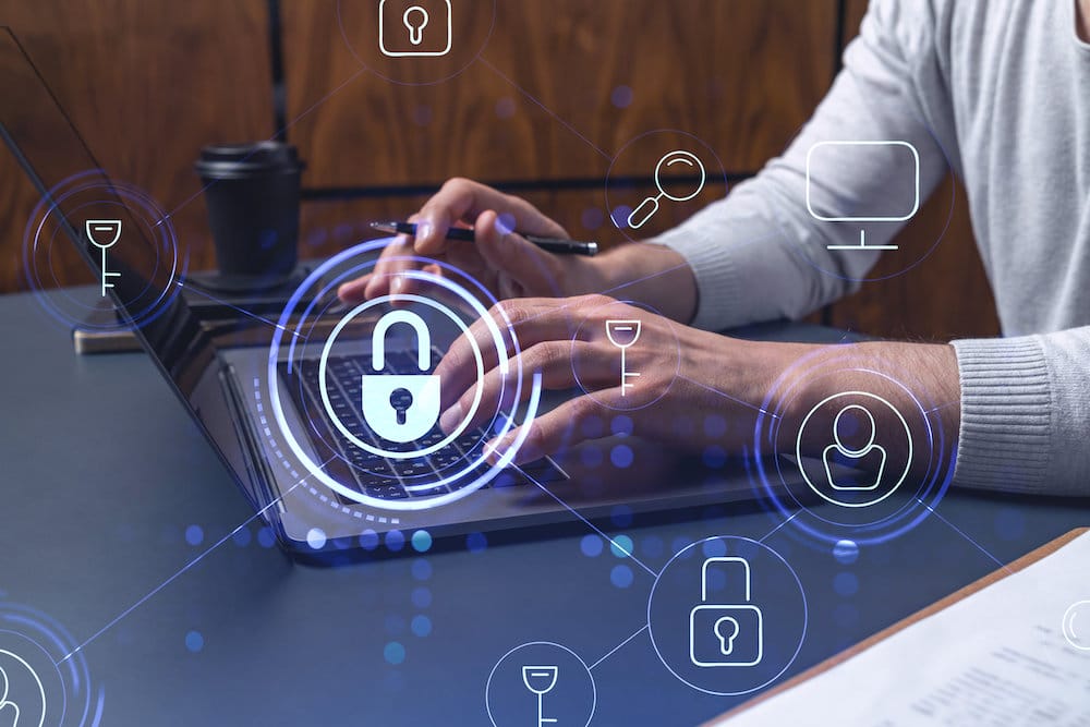 A programmer is typing a code on a keyboard to protect a cyber security from hacker attacks and save clients confidential data. Padlock Hologram icons over the typing hands.