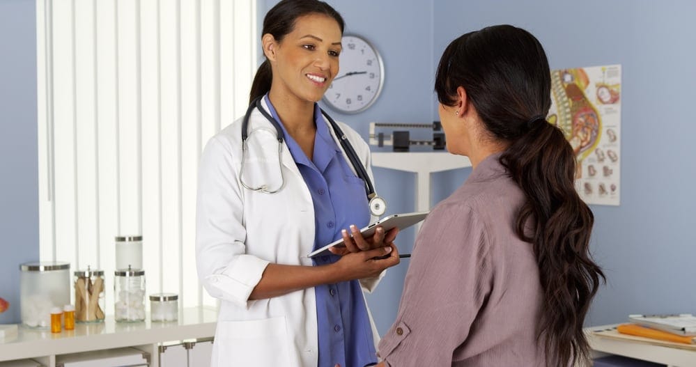 African American gynecologist talking to patient with tablet