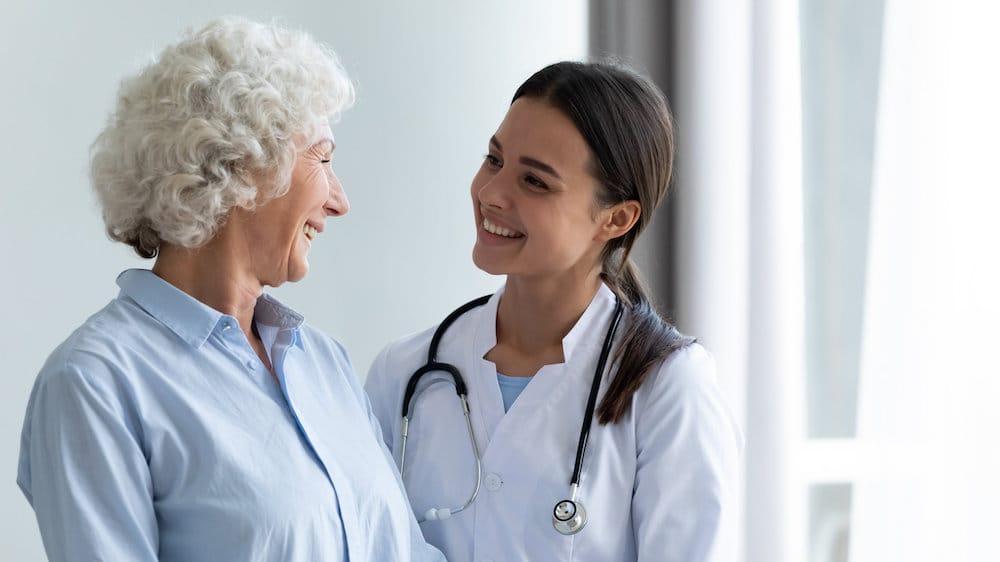 Smiling caring young female nurse doctor caretaker assisting happy senior grandma helping old patient in rehabilitation recovery at medical checkup visit, elder people healthcare homecare concept