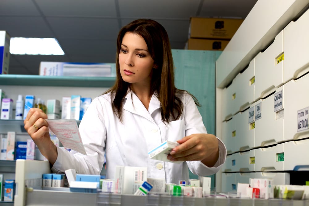 Good looking woman pharmacist working in pharmacy with medicine and prescription