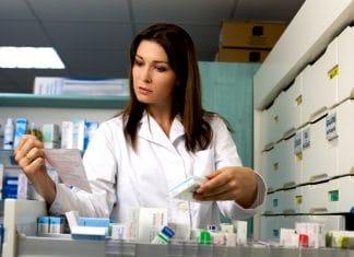 Good looking woman pharmacist working in pharmacy with medicine and prescription