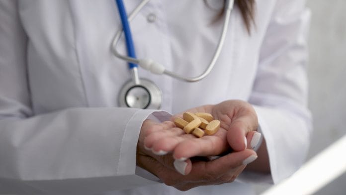 The pills are in the doctor's hands. Hands in medical gloves hold pills.