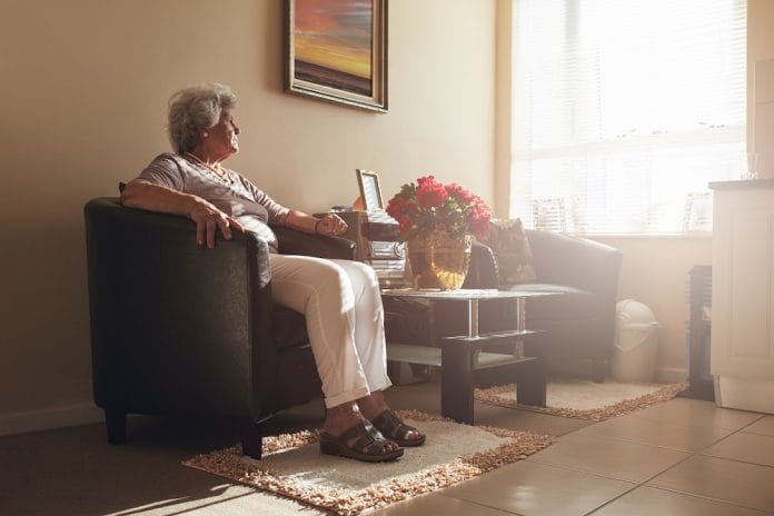 Senior woman sitting alone on a chair at home. Retired woman relaxing in living room.