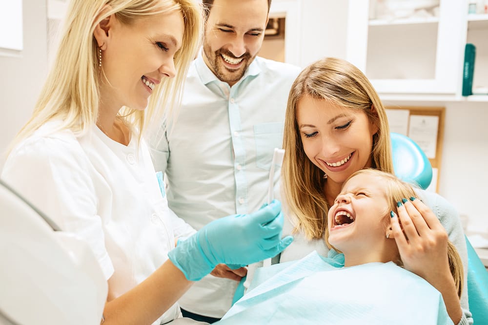 Dentist treating cute blonde child in his surgery.