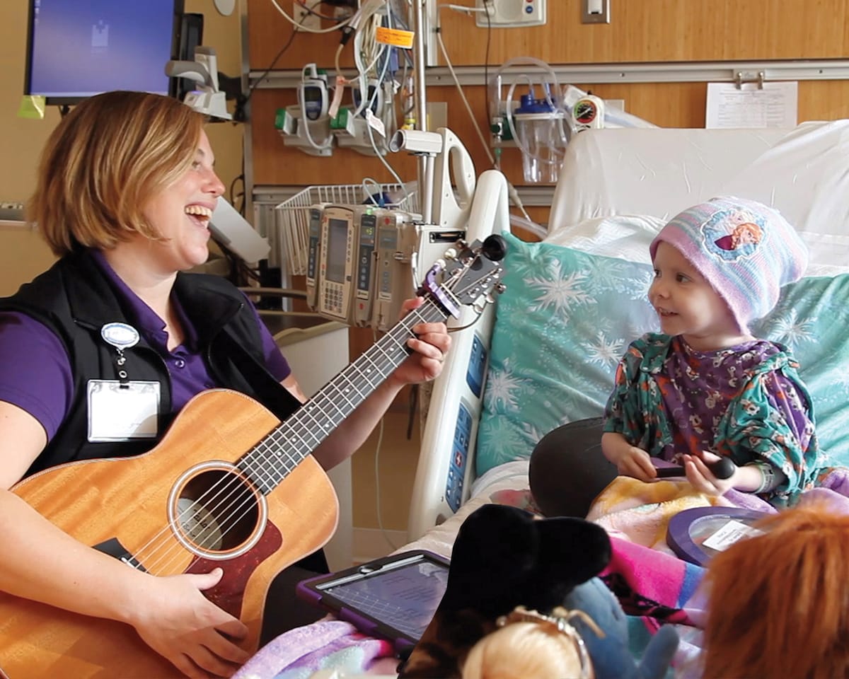 Nurse playing the guitar for a pediatric patient
