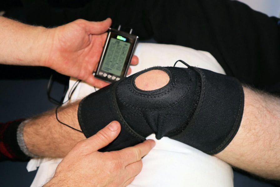 A physical therapist working with someone to rehab their knee after surgery; ROMTech’s PortableConnect can help speed up the recovery process and improve ROM faster.