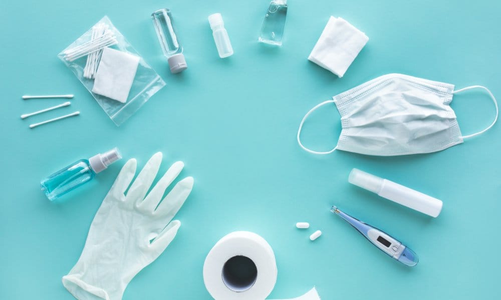 Cotton swabs, plastic bottles filled with liquids, latex gloves, gauze, pills, a medical mask, and a thermometer in a circle.