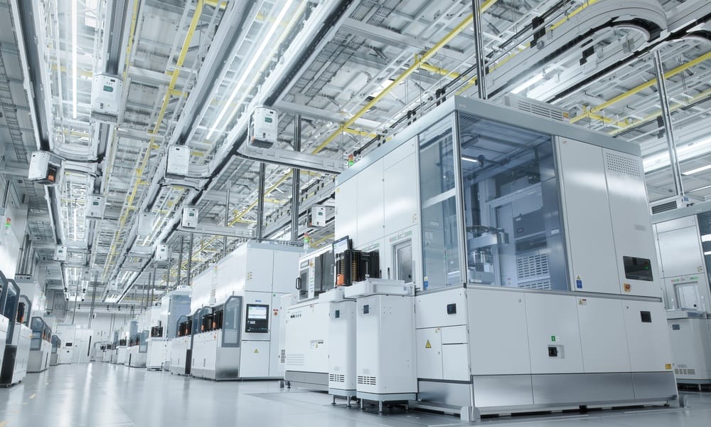 A view of a manufacturing facility from the aisleway. There's cubicles where certain parts are made and produced.