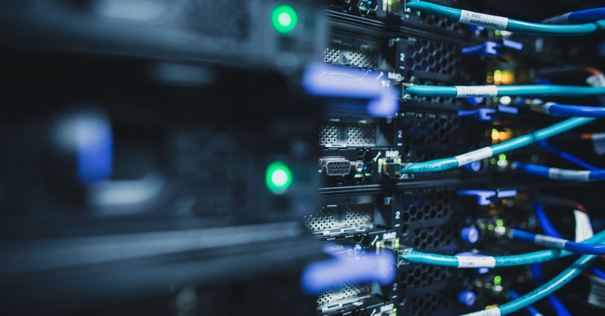 A close-up of an IT server rack infrastructure. There are various wires, buttons, and lights indicating it's working.