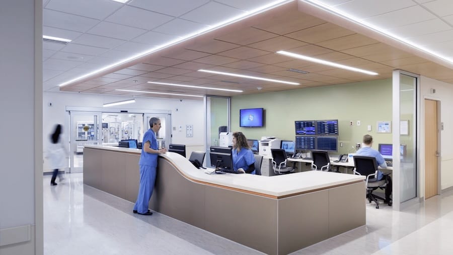 Nurses working at a hospital station with computers in a clean, modern medical environment.