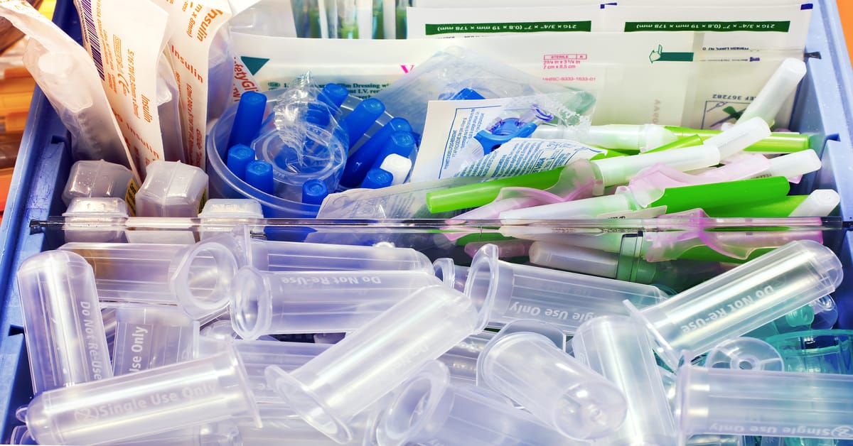 An assortment of plastic components for lab work, including caps, containers, and syringes in sterile containers.