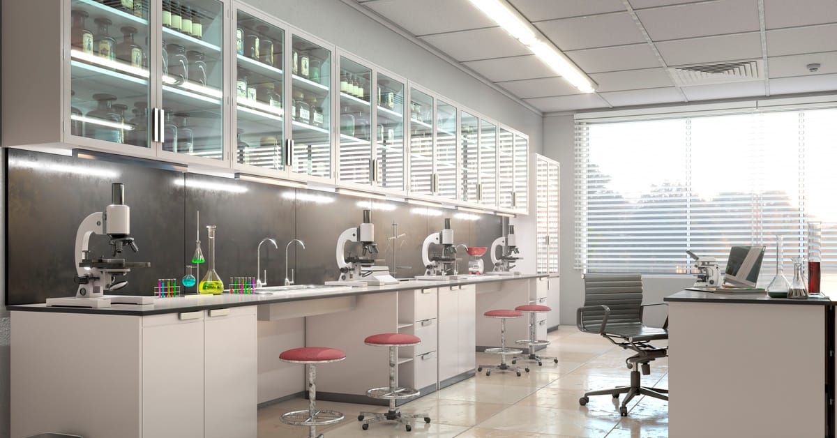 A bright laboratory with microscopes on a long counter, glass cabinets of labware, test tubes, and stools.